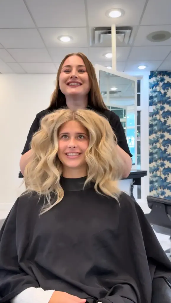 A stylist with a smiling client after a blonde balayage and blowout