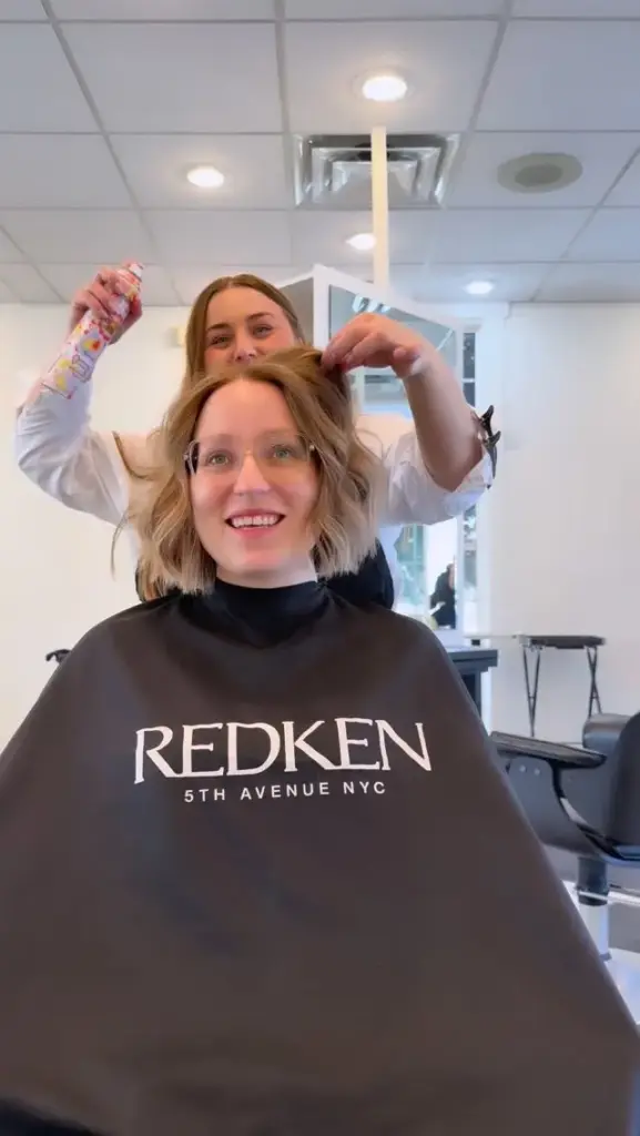 A stylist and a smiling client in the chair after a cut and style